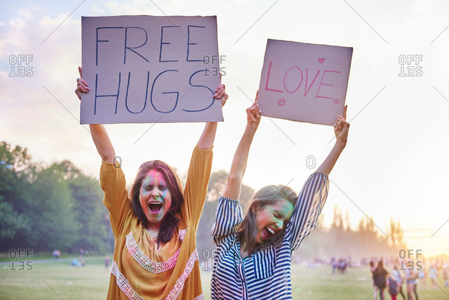 Young women dancing holding up love and free hug signs at Holi Festival