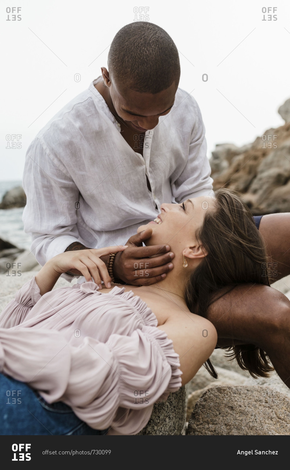 An interracial couple hangs out on rock formation in a cloudy day