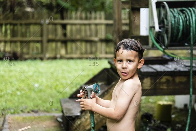 Soaking wet boy holding hose
