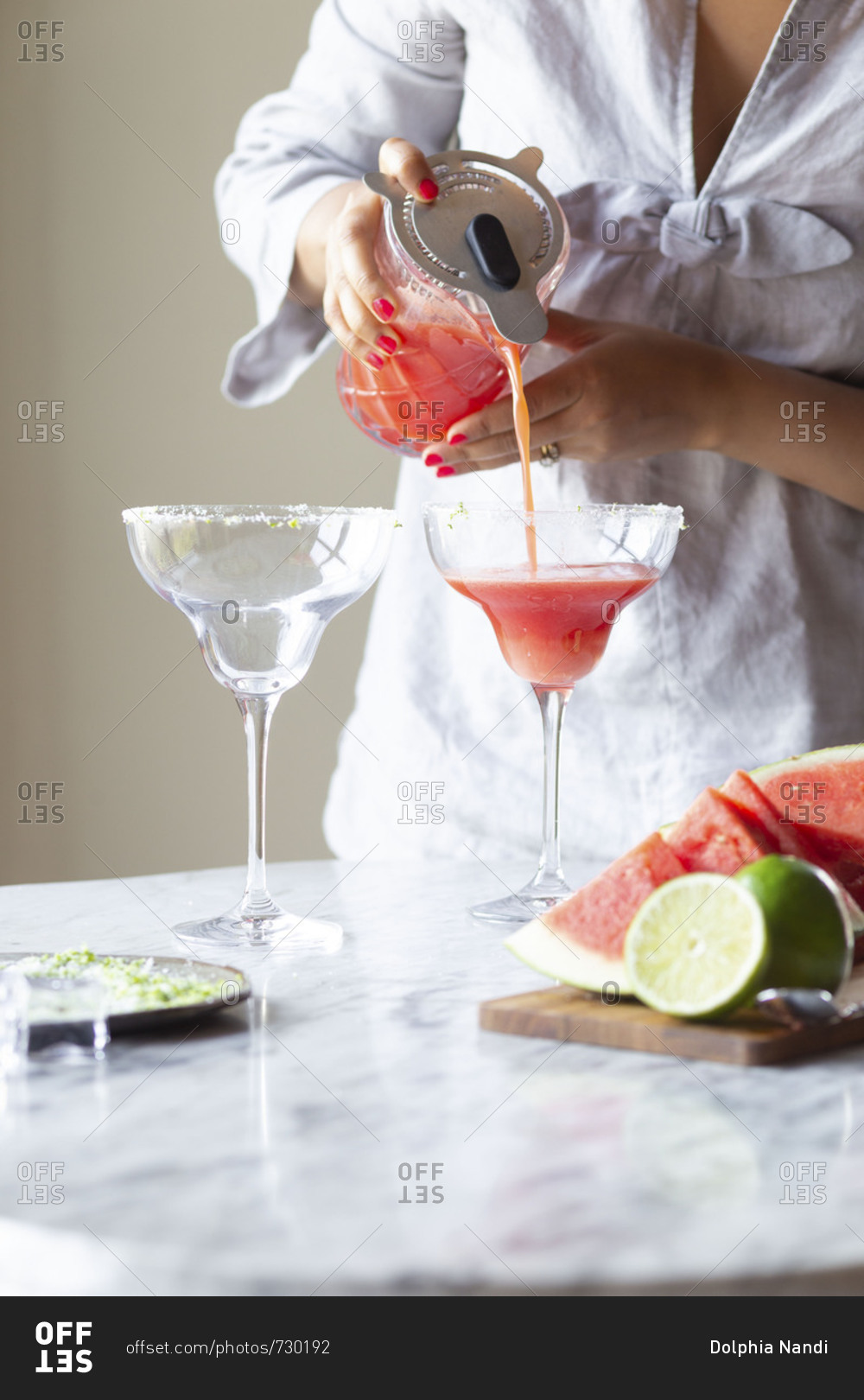 Woman pouring margarita drink from a pitcher into a glass