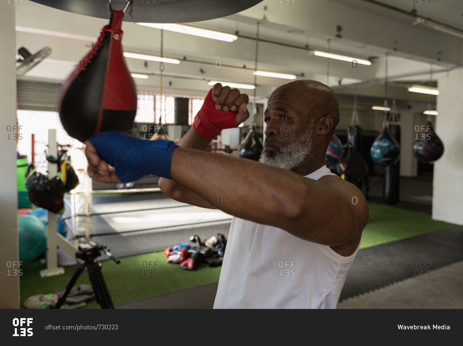 Senior man punching the speed bag in the fitness studio
