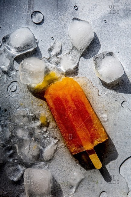 A melting ice lolly lying between ice cubes (top view)