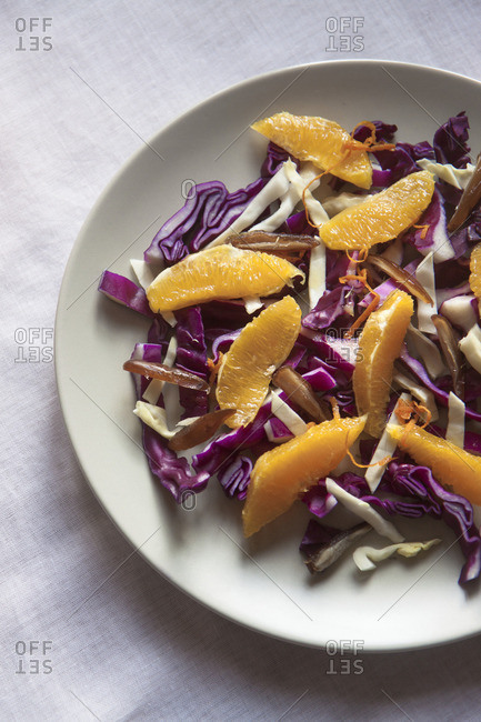 A raw and healthy winter salad with red cabbage, white cabbage, dates, orange, zest of orange