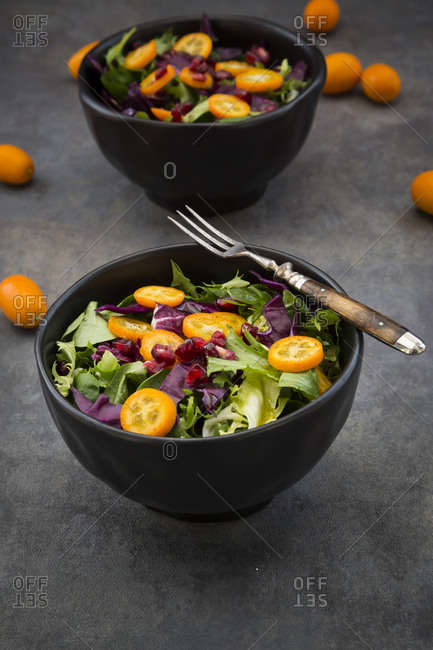 Bowl of mixed green salad with red cabbage- kumquat and pomegranate seeds