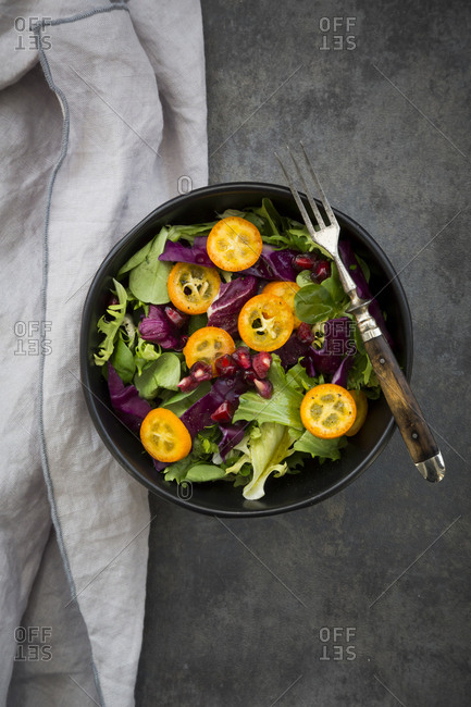 Bowl of mixed green salad with red cabbage- kumquat and pomegranate seeds