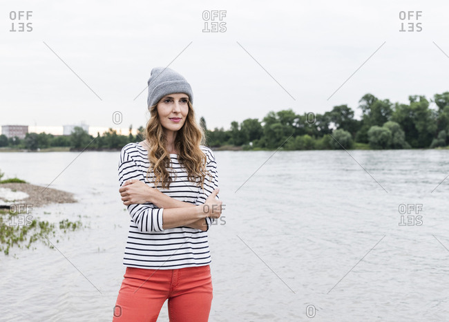 Portrait of woman wearing wooly hat standing at the riverside