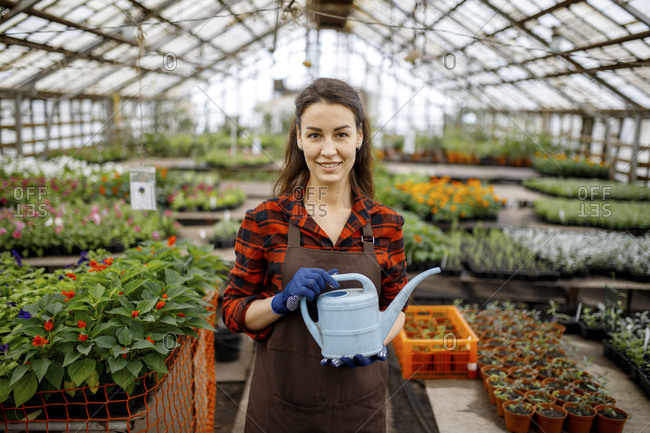 Woman standing wearing apron in a greenhouse