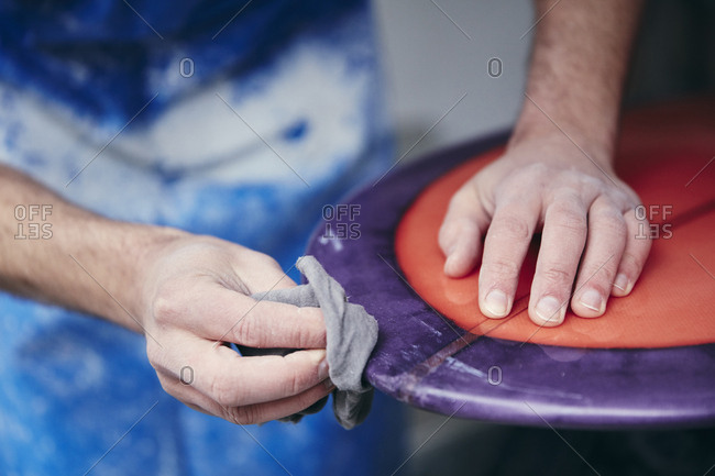 Man sanding and shaping a surfboard in a workshop
