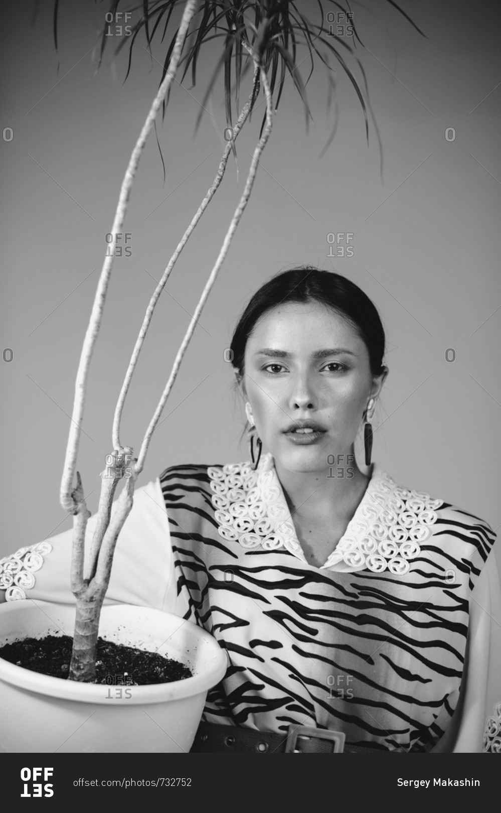 Black and white portrait of a woman in a tiger print dress holding a plant