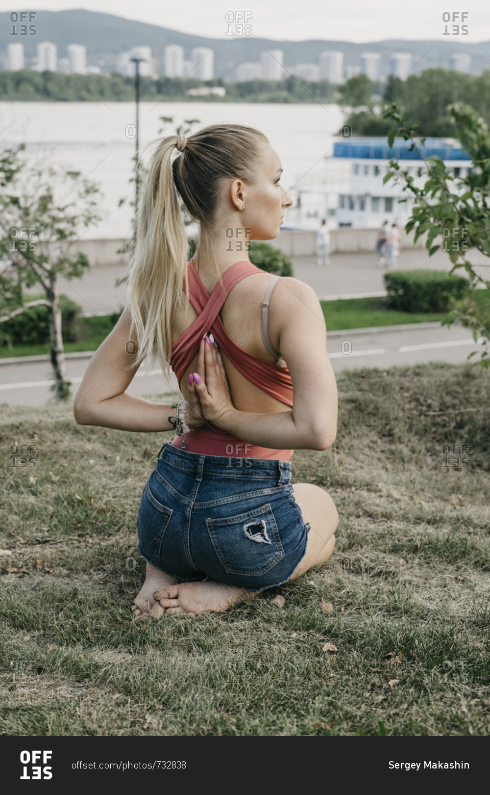 Young blonde woman sitting while doing reverse prayer yoga pose