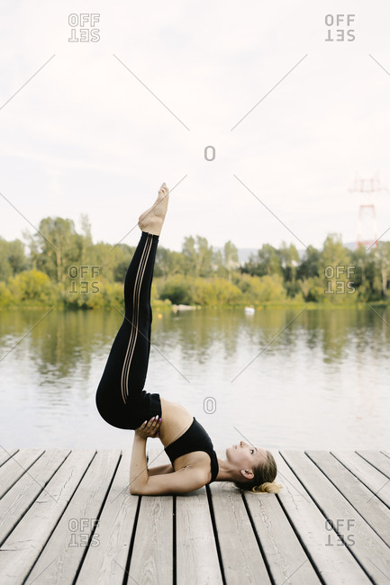 Young blonde woman lifting legs in the air on riverfront