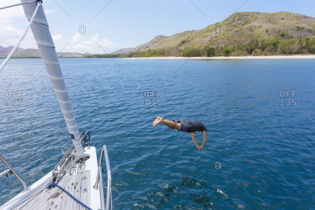 Man diving in water from boat, Lombok, Indonesia