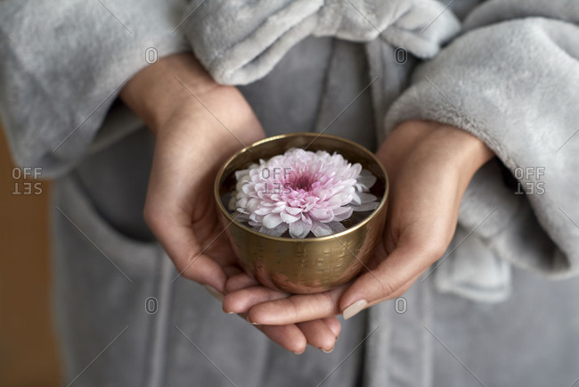 Hands holding elegant flower in metal bowl