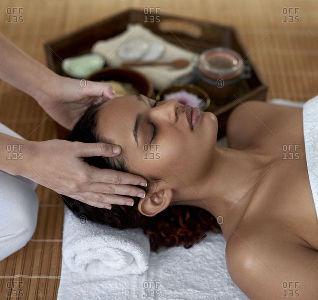beautiful mixed race woman closing her eyes peaceful and relaxed during her head massage with professional therapist
