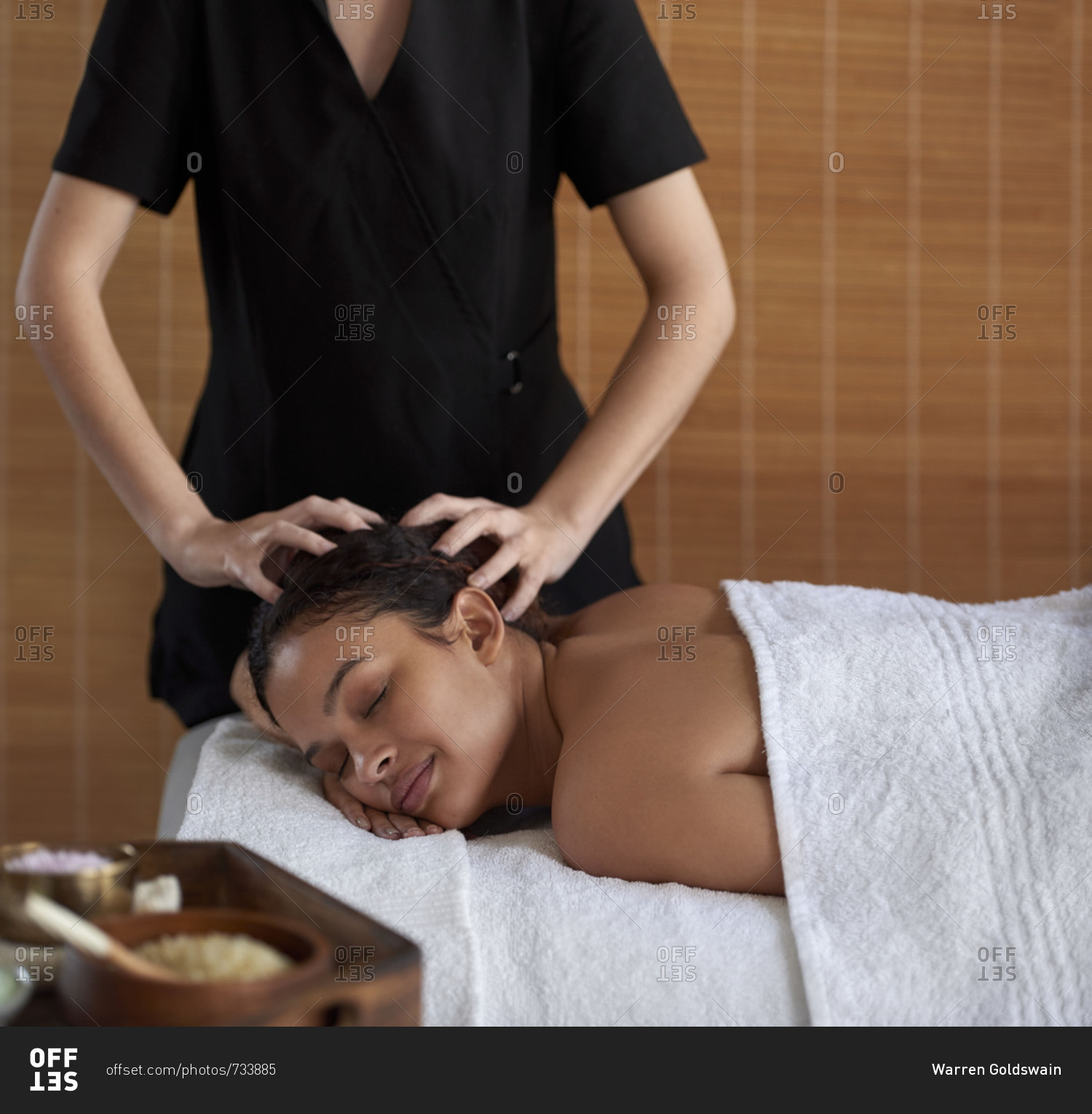 Professional massage therapist giving beautiful woman head massage in spa treatment room