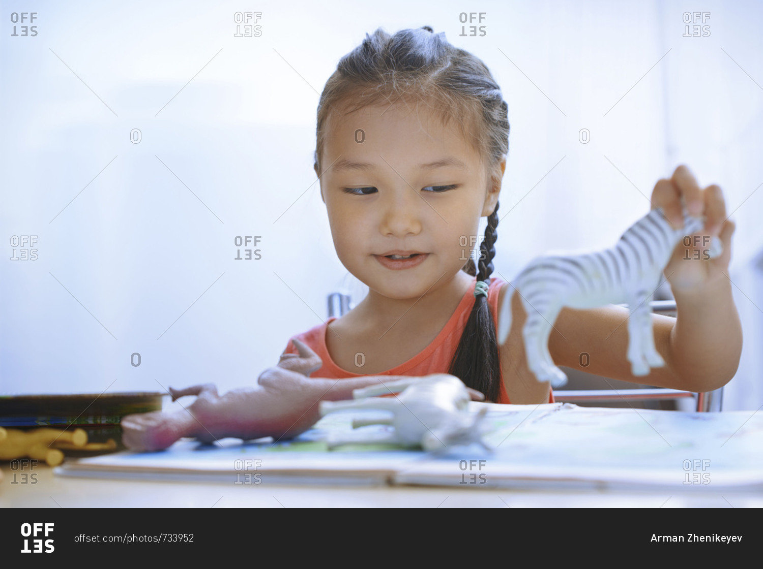 Cute girl at the table playing with animal and dinosaur toys