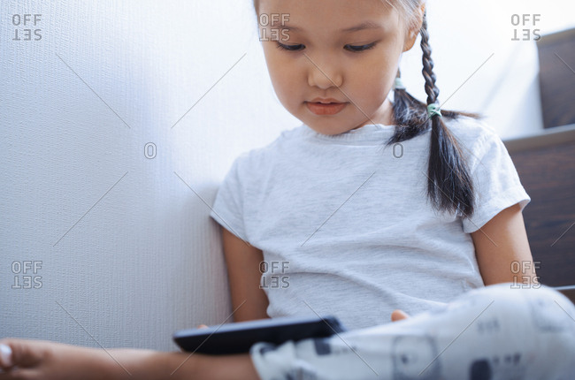 Cute 4-5 year old girl using tablet computer on stairs at home