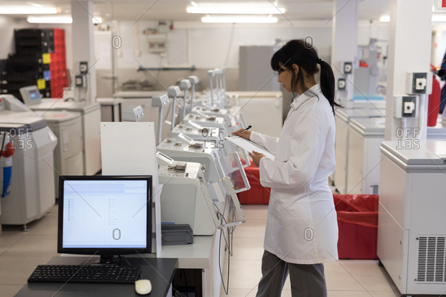 Laboratory technician writing on clipboard in blood bank
