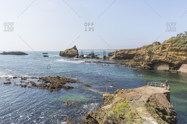 People looking into the water at Port Vieux beach with Rocher de la Vierge in background, Biarritz, France