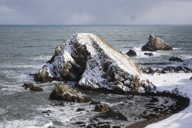 Snow covered rock formation on coast