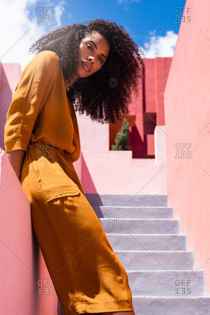 Black woman leaning in a colorful geometric building wall