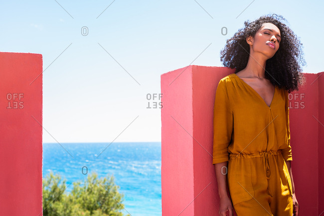 Black woman leaning in a colorful geometric building wall