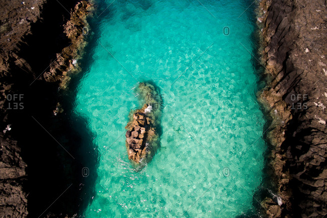 Scenic aerial view of vibrant turquoise water of small bay surrounded by rocky mountains on summer sunny day in La Graciosa, Canary Islands