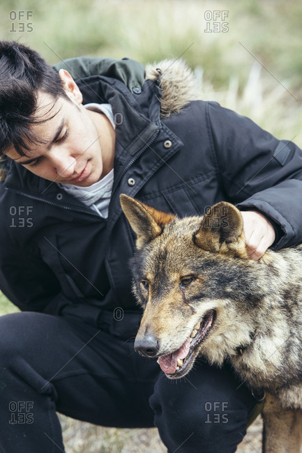 Young handsome man stroking wolf