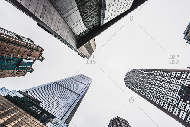 From below shot of high-rise contemporary skyscrapers with glass reflecting daylight under clear sky
