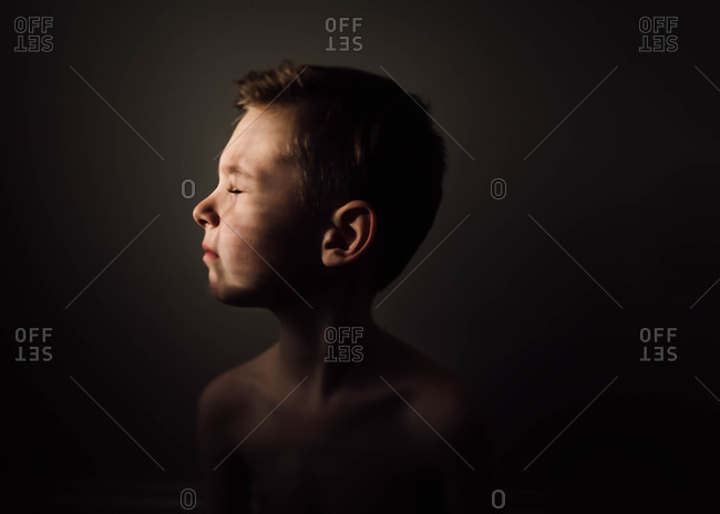 Young boy looking toward sunlit window with eyes closed