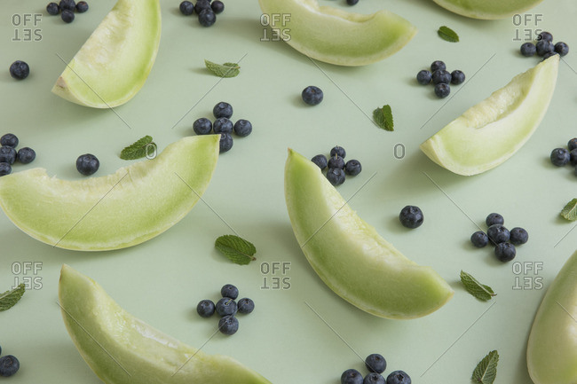 Slices of honeydew melon arranged with blueberries and mint leaves