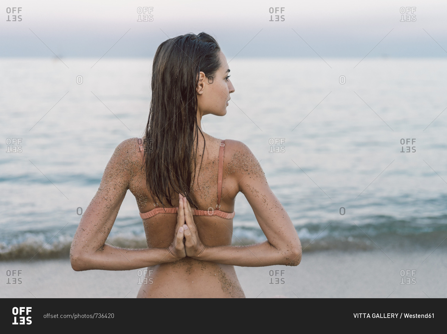 Beautiful woman on the beach practicing yoga stock photo