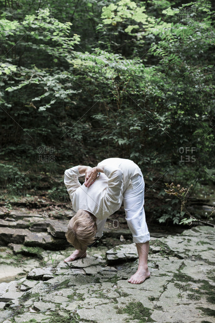 Senior woman doing yoga- bending over