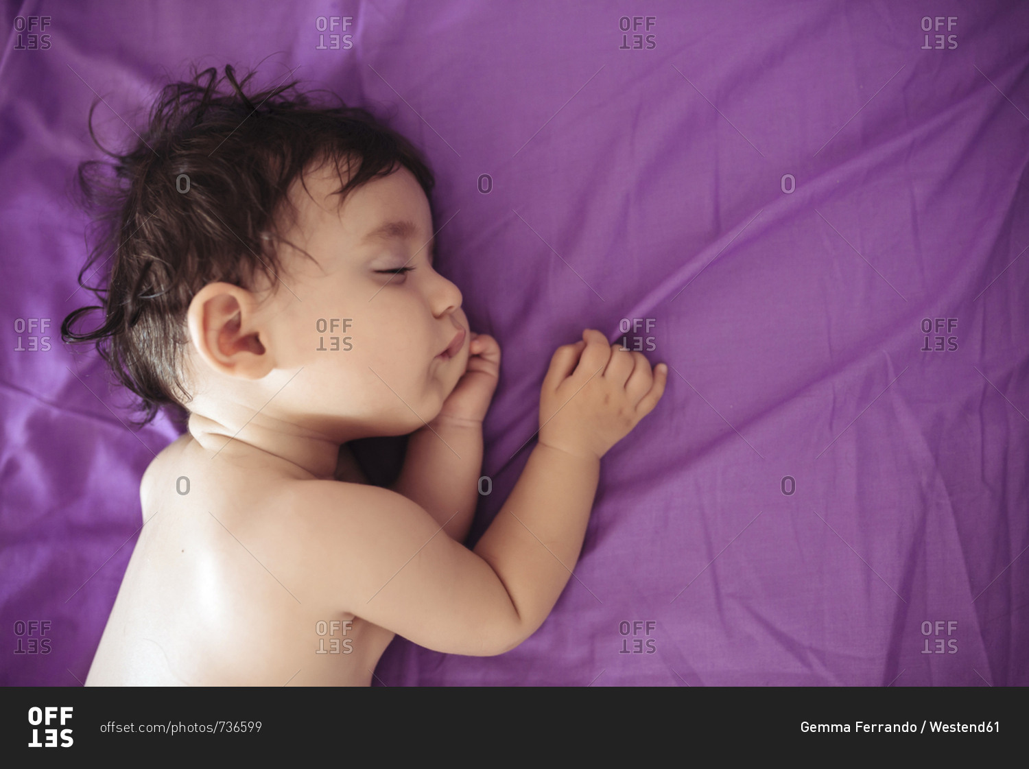 Sleeping baby girl on purple bed sheet