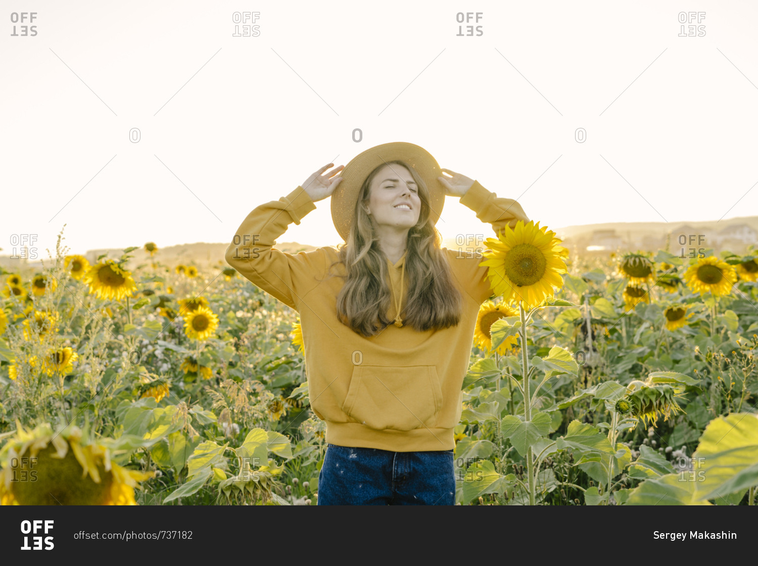 Woman in a straw hat smiling on the field with sunflowers