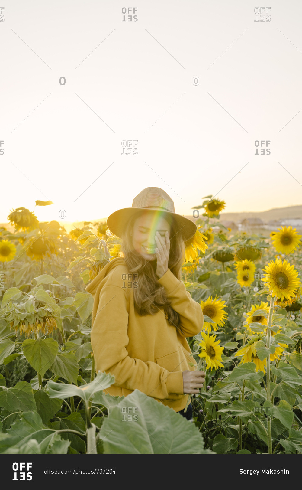 Portrait of a beautiful young woman is happy and smiling at the field of sunflowers