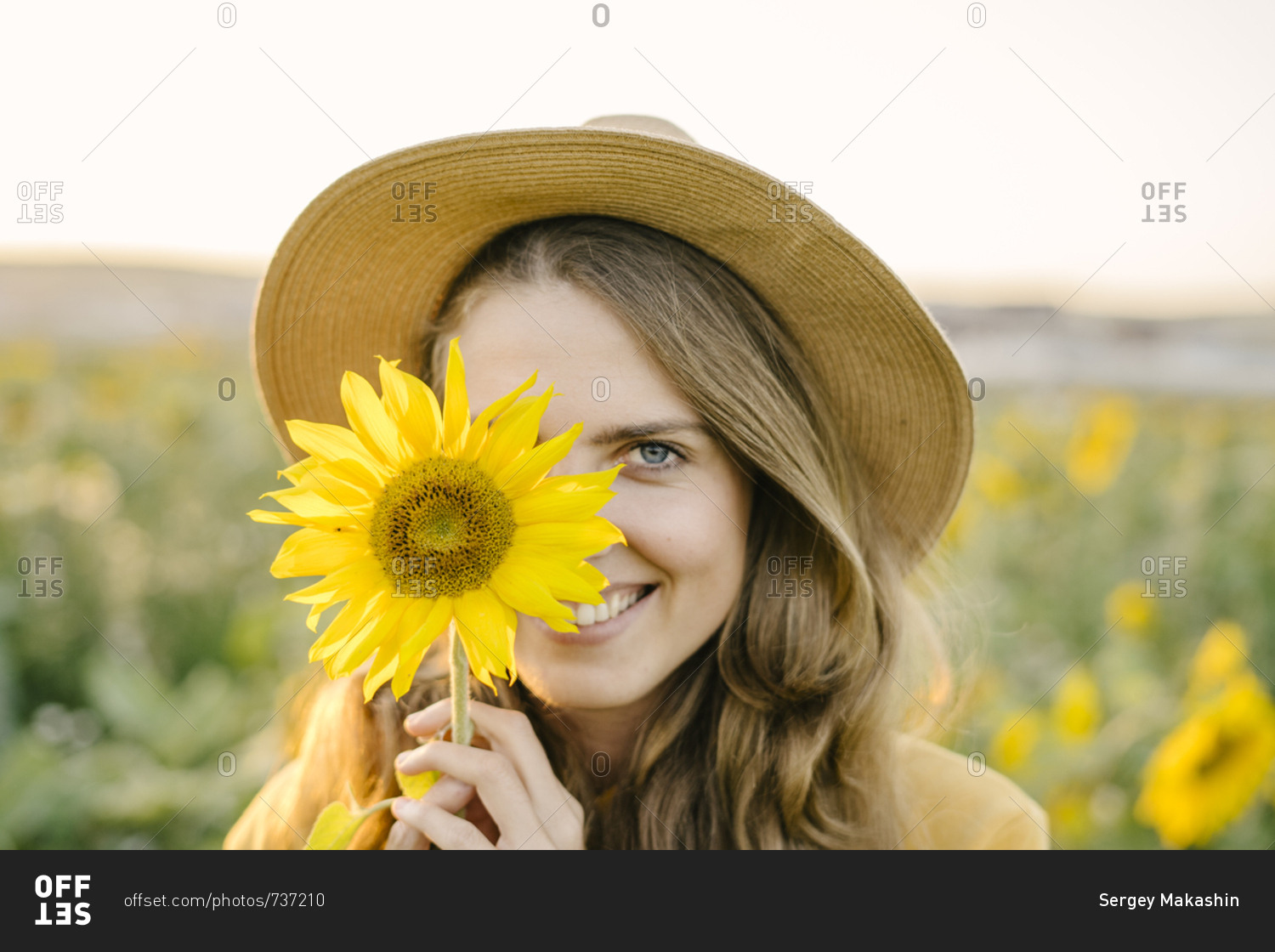 Portrait of a beautiful young woman is happy and smiling at the field of sunflowers