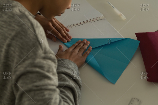 Close-up of kid making paper plane with craft paper in training institute