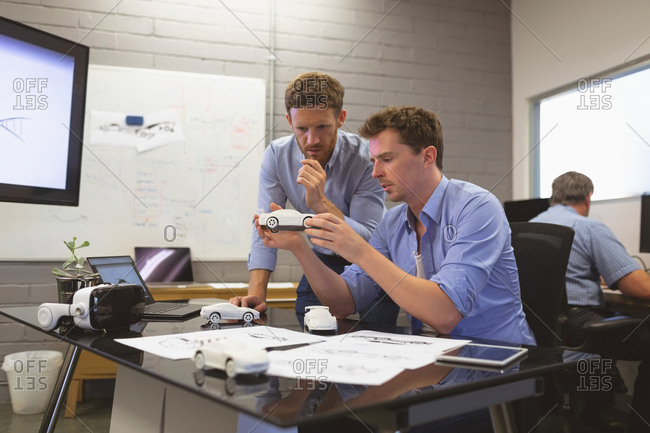 Business colleagues discussing over car model in office