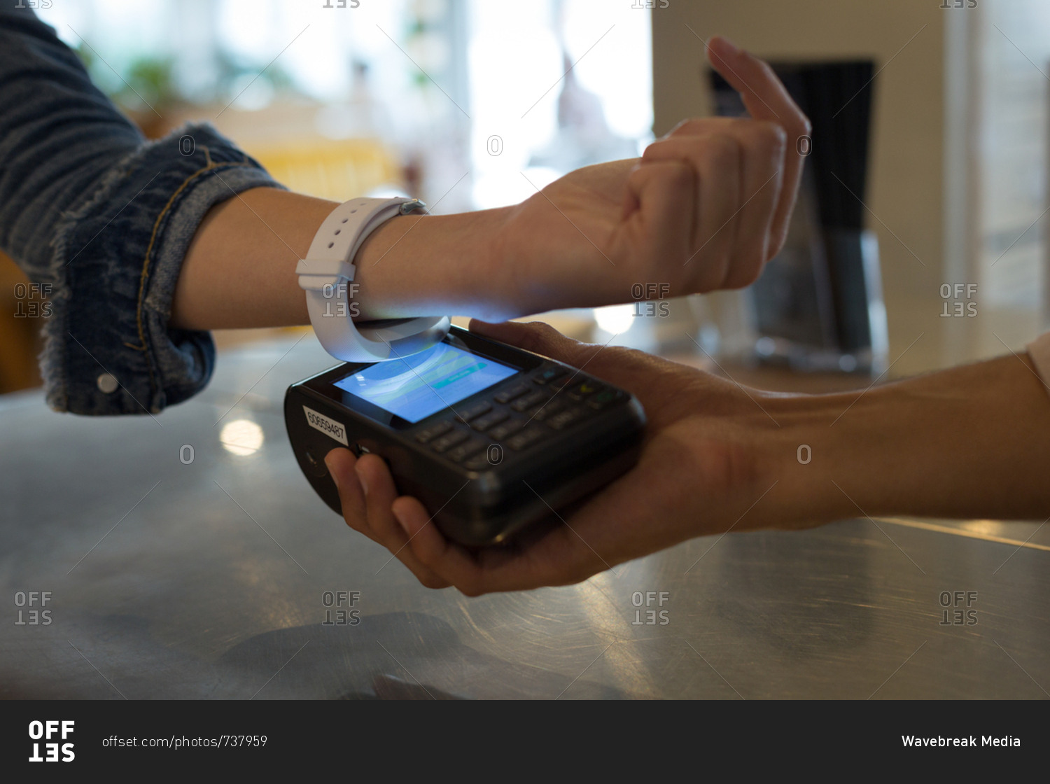 Close-up of woman paying with NFC technology on smartwatch in cafe
