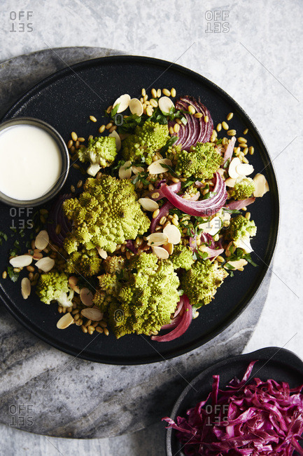 Roasted romanesco cauliflower salad with roasted red onions and ancient grains (roasted farro). garnished with toasted almonds and a lemon yogurt sauce. side of picked red cabbage.