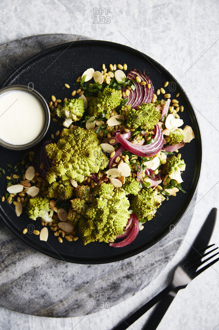 Roasted romanesco cauliflower salad with roasted red onions and ancient grains (roasted farro). garnished with toasted almonds and a lemon yogurt sauce. side of picked red cabbage.