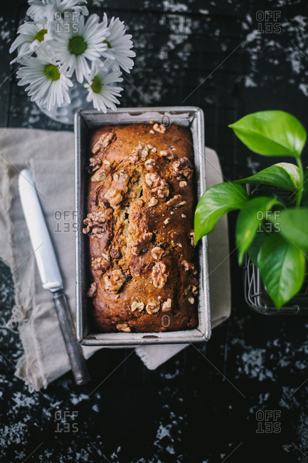 Loaf of freshly baked bread topped with walnuts in a baking pan