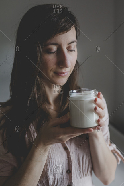 A young woman smelling the scented candle that she just crafted