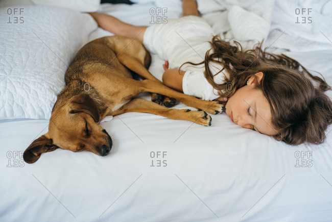 Girl sleeping on the bed with her pet dog
