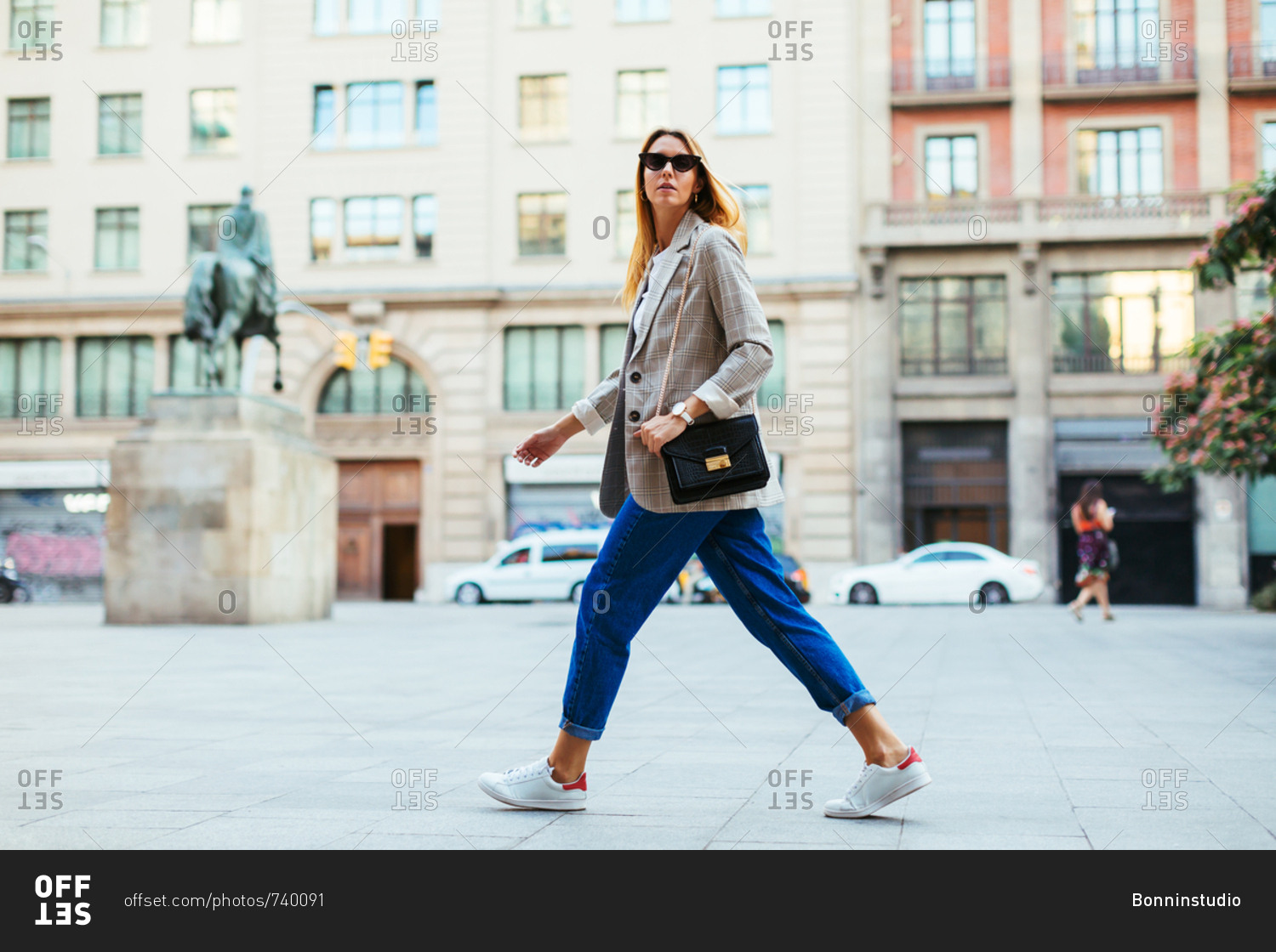 Blonde stylish woman striding across the street.