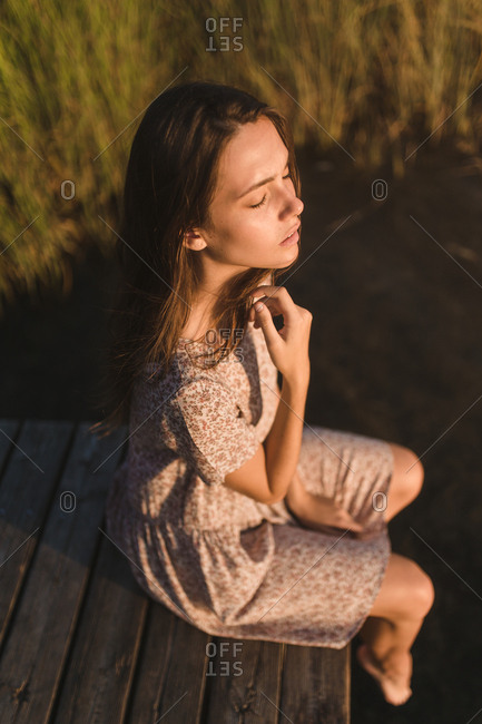Portrait of young brunette girl with long hair bun observing and relaxing in a lake in a sunset of summer