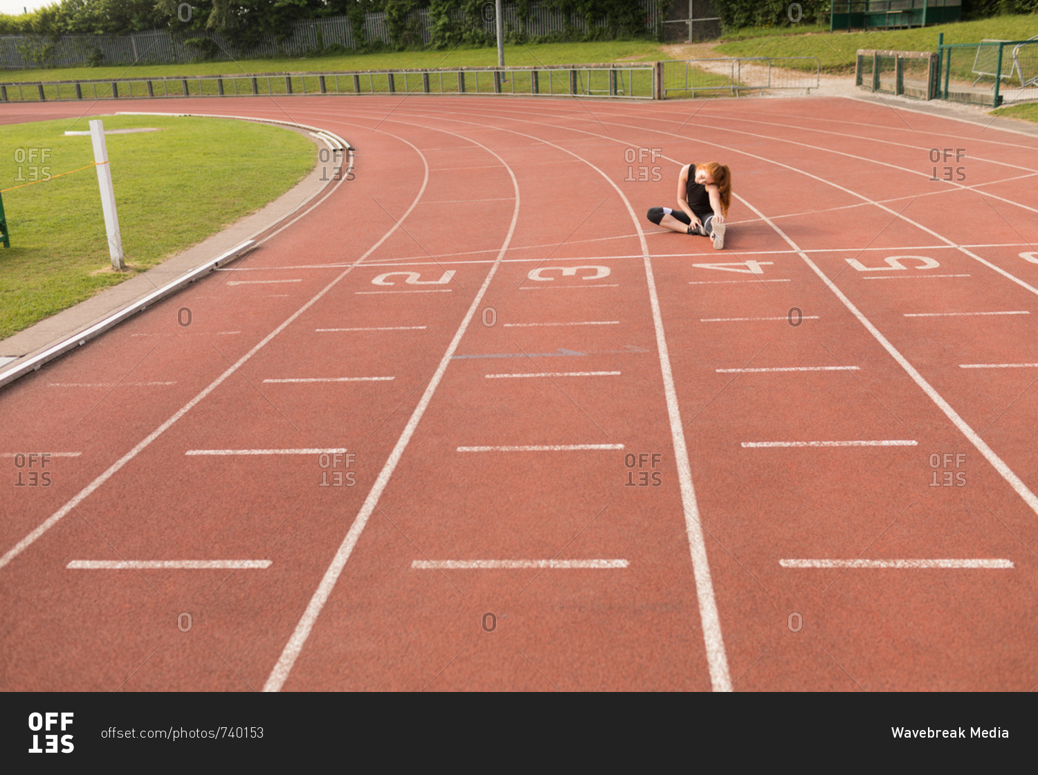 Young female athletic exercising on running track