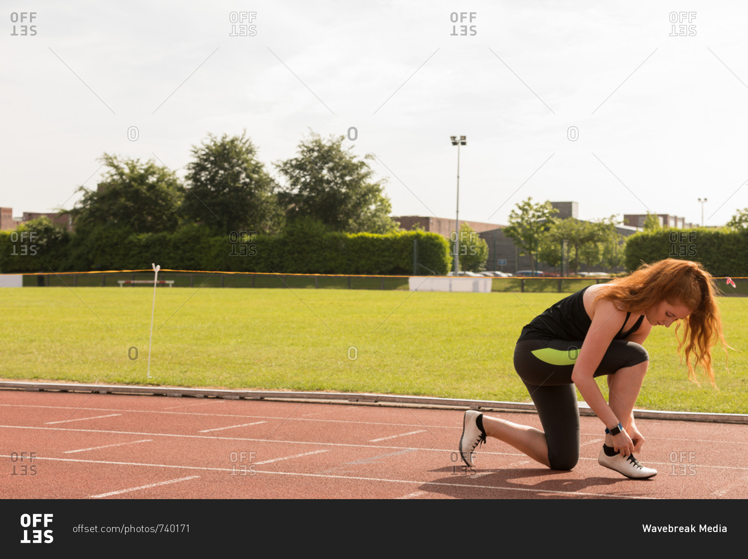 Young female athletic tying shoe laces on a running track