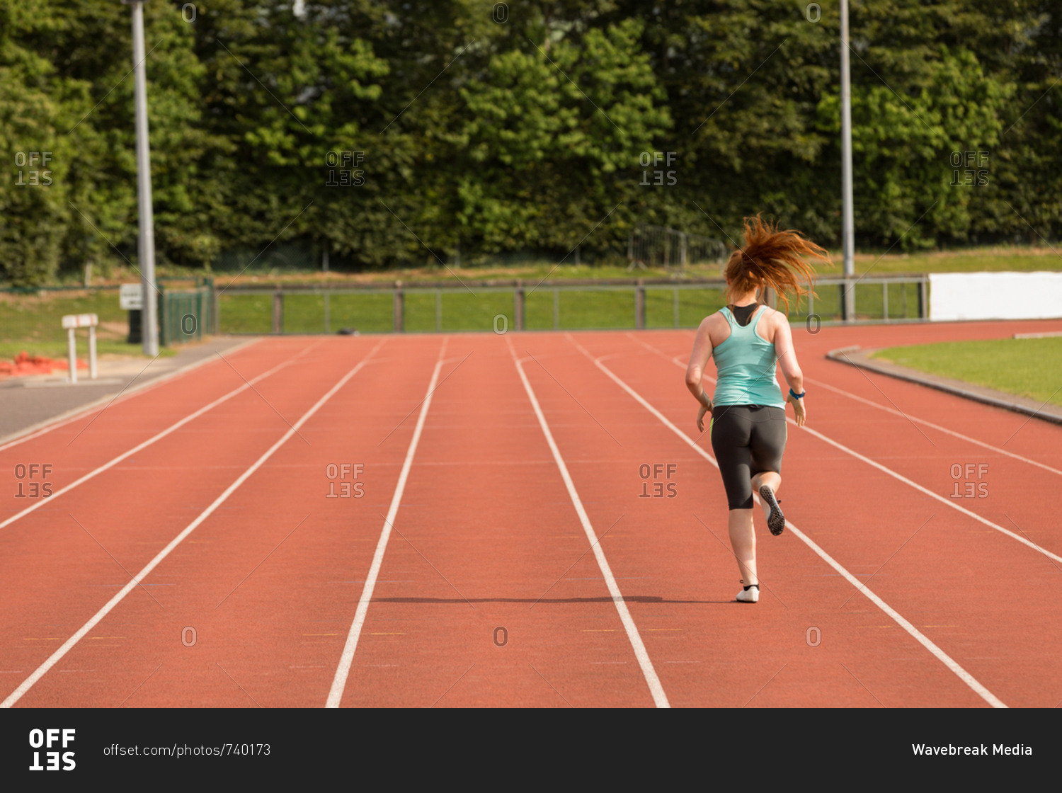Rear view of female athletic running on sports track
